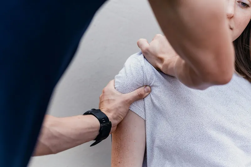 Practitioner's hands assessing a client's shoulder during a NeuroKinetic Therapy movement assessment